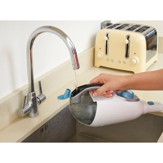 BLACKDECKER FSMH1351SM steam cleaner water tank being filled at a kitchen sink, close-up side view.