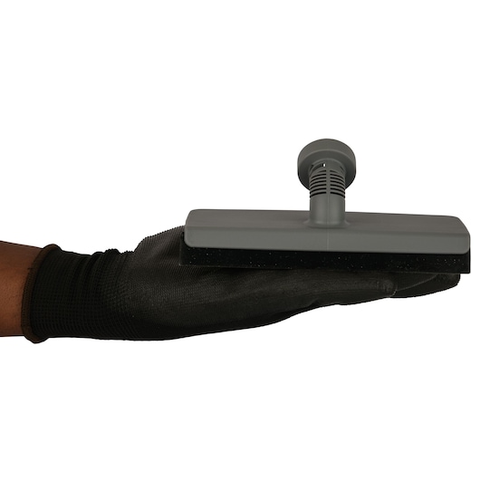 BLACKDECKER FSMH21A flat gray cleaning brush held in gloved hand, side angle, photography.