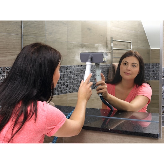 BLACKDECKER FSMHBA steam cleaner used on a bathroom mirror, handheld and generating visible steam.