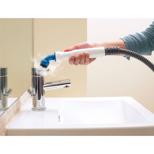 BLACKDECKER FSMHKA handheld steam cleaner cleaning a chrome faucet in a bathroom.