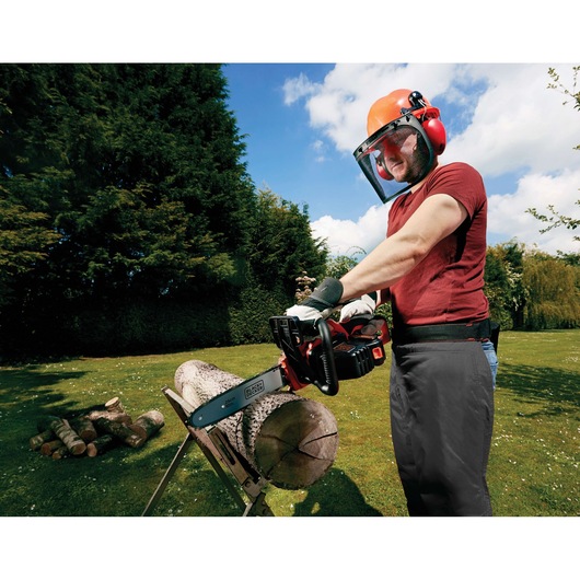 Photo of BLACK+DECKER GKC1825L20 cordless chainsaw in use, cutting a log outdoors on a sawbuck.