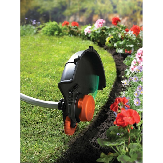 BLACKDECKER GL7033 grass trimmer in use, edging lawn near flower bed, close-up outdoors.