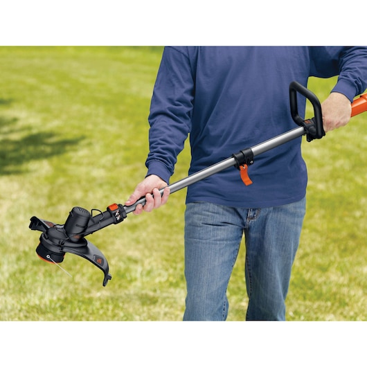 Photo of BLACKDECKER GLC3630L20 cordless grass trimmer being held outdoors by a person on a lawn.