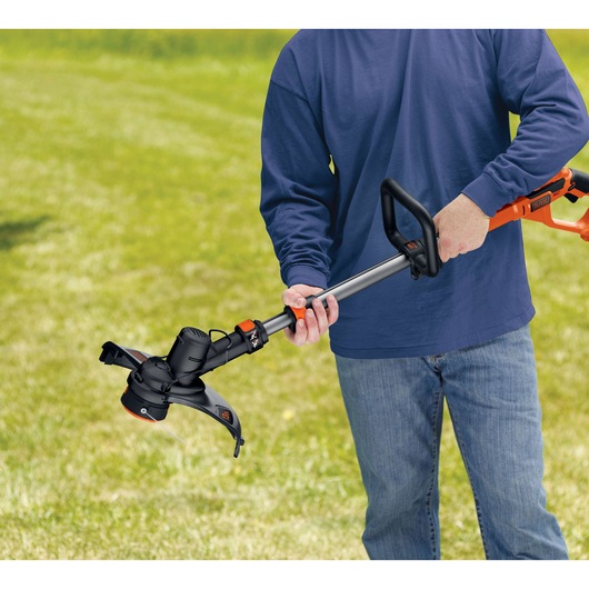 Photo of BLACK+DECKER cordless grass trimmer, SKU GLC3630L20, being used outdoors on a lawn.
