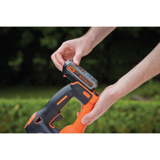 BLACKDECKER GTC18452PC hedge trimmer with 18V lithium battery being installed outdoors.