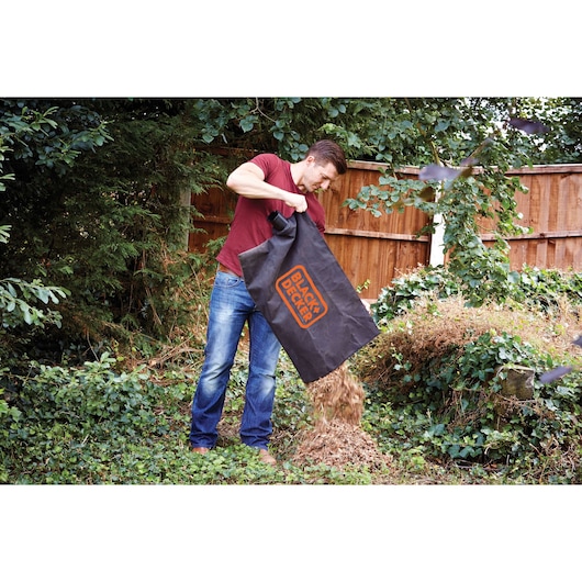 BLACKDECKER GW2500 garden vacuum bag used to empty mulch onto a leafy yard, outdoor setting.