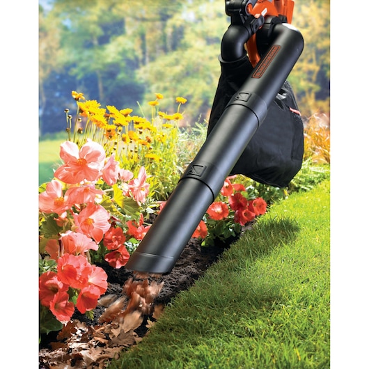 BLACK+DECKER GWC3600L20 leaf blower in use near flowers and lawn, collecting fallen leaves.