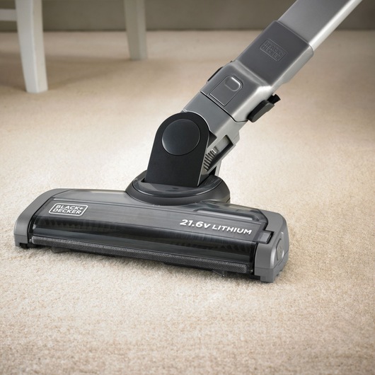 Close-up of a BLACK+DECKER cordless vacuum cleaner with a 21.6V lithium battery head on a light carpeted floor.