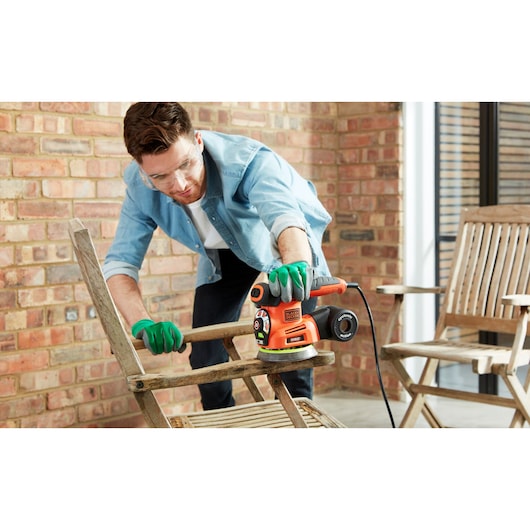 Photo of BLACKDECKER KA280LSA orange multi-sander used on a wooden chair in a patio setting.