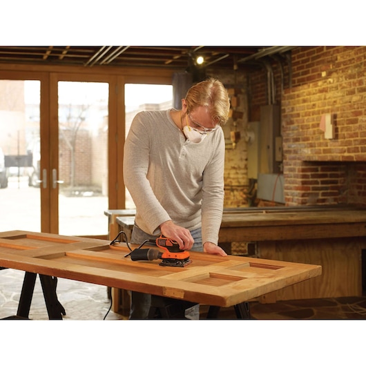 BLACKDECKER KA450 sander used on wooden door in workshop setting.