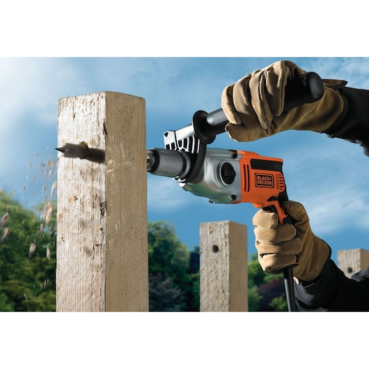 BLACK+DECKER KR911K drill in use on wooden post outdoors, close-up side angle.