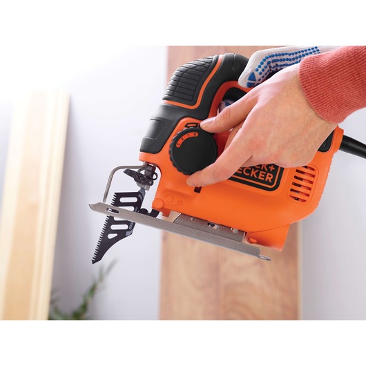 BLACK+DECKER KS901PEK orange jigsaw in use, close-up side view on wood surface.