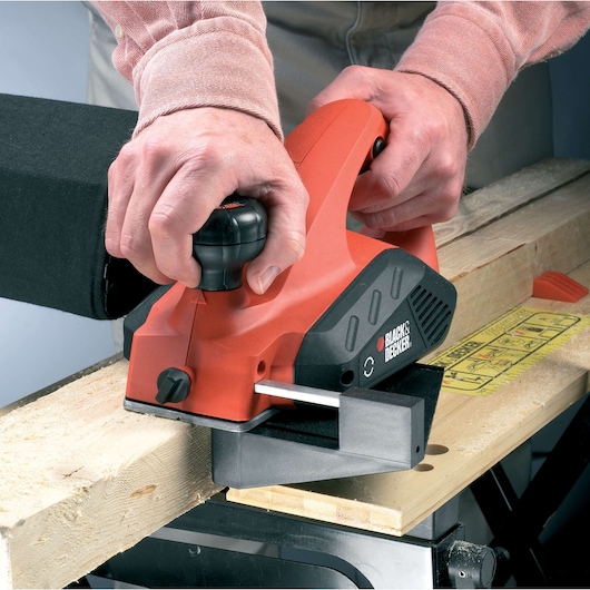 BLACKDECKER KW712KA electric planer used on wood plank, close-up angle.