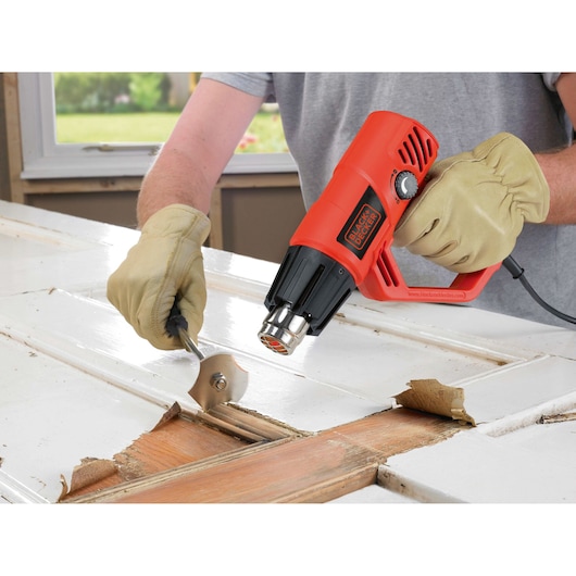 BLACKDECKER KX2001K heat gun in use for paint removal on a wooden door.