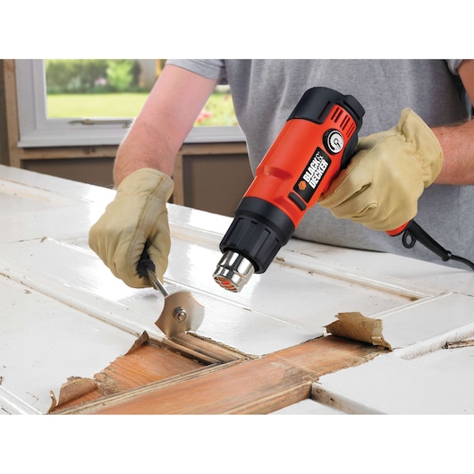 BLACKDECKER KX2200K heat gun used to strip paint from wooden door, close-up photography.