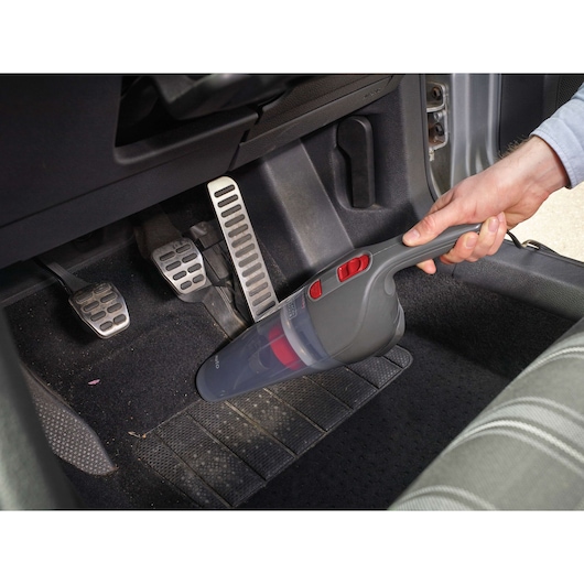 BLACKDECKER NV1200AV handheld vacuum cleaning car interior near pedals.