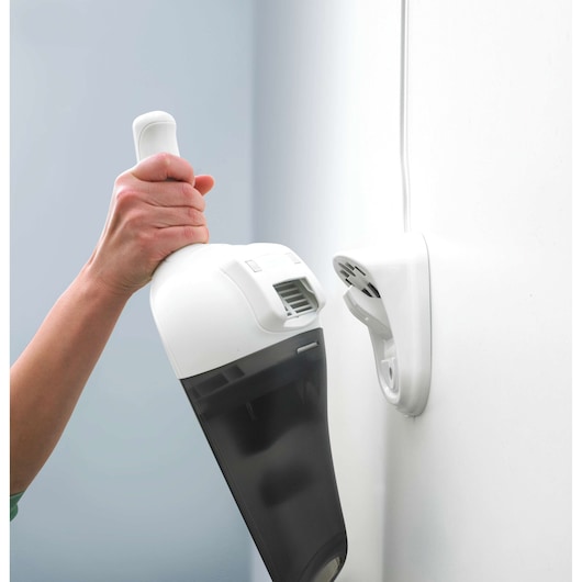 BLACKDECKER NV2410N handheld vacuum cleaner being placed on wall-mounted charger, close-up side view.