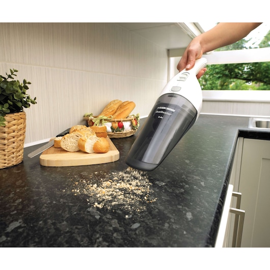 BLACKDECKER NV2420N handheld vacuum cleaning crumbs from a kitchen counter next to bread and a cutting board.