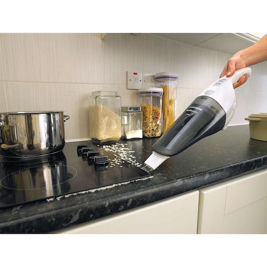 BLACKDECKER NV2420N handheld vacuum cleaning rice on kitchen countertop, side angle.