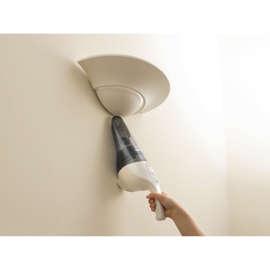 BLACK+DECKER NV2420N handheld vacuum cleaner cleaning a wall sconce, side angle.