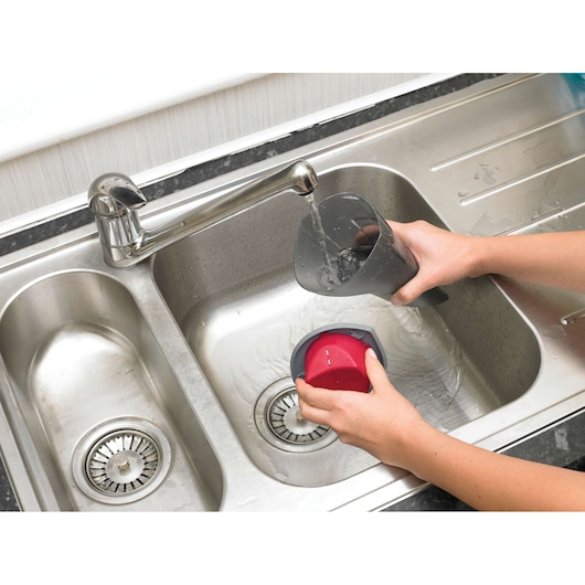 BLACKDECKER NV3610N vacuum dust container and filter being washed in a sink, close-up top view.