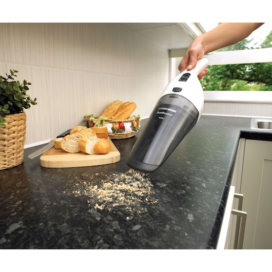 BLACKDECKER NV4820N handheld vacuum cleaning bread crumbs on kitchen counter near breadboard.