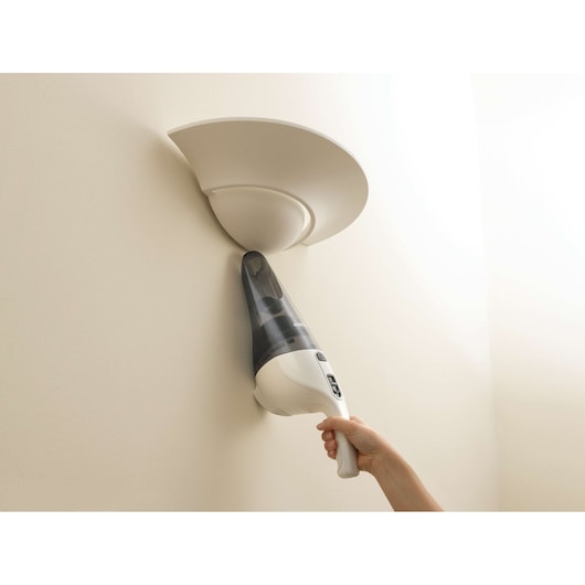 Photo of BLACKDECKER NV4820N handheld vacuum cleaning a wall-mounted light fixture.