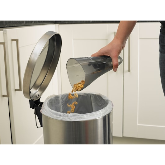 Photo of BLACKDECKER NV7210N vacuum dustbin being emptied into a stainless steel trash can in a kitchen.
