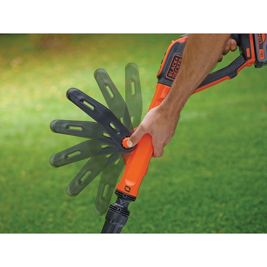 BLACK+DECKER STC1840EPC grass trimmer being adjusted, orange and black handle shown outdoors.