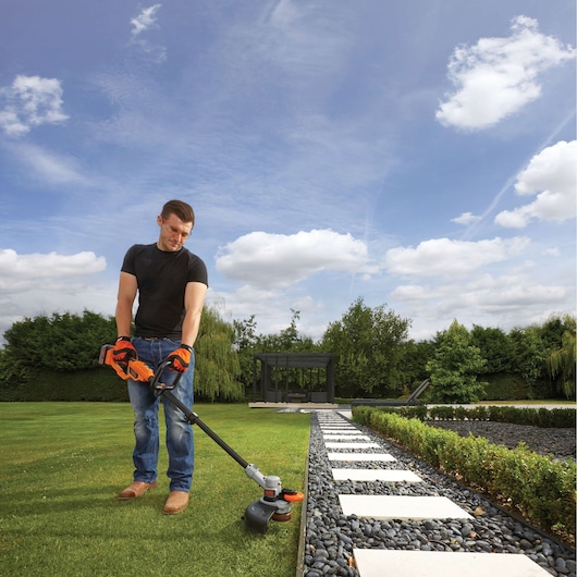 BLACKDECKER STC1840 grass trimmer in use on lawn near stone path in garden.