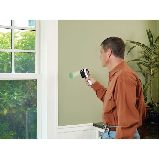 BLACKDECKER TLD100 thermal leak detector used on interior wall near window in home setting.