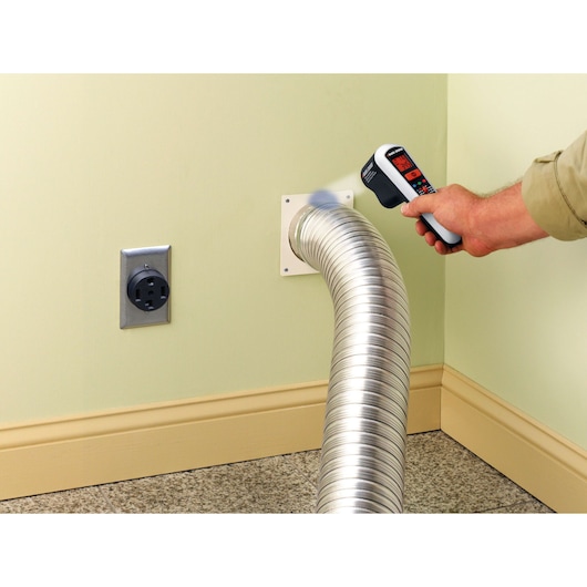 BLACK+DECKER TLD100 thermal leak detector measuring air vent in corner near electrical outlet.