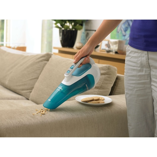 BLACKDECKER WD9610N handheld vacuum in turquoise and white cleaning crumbs from beige sofa.