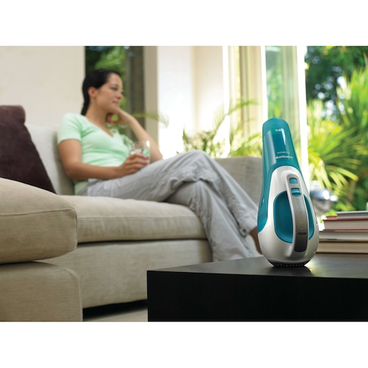 BLACKDECKER WD9610N handheld vacuum in teal and white on black table in living room setting.