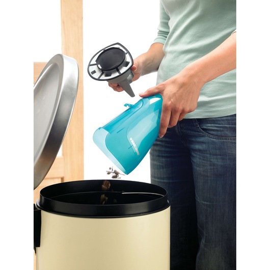 BLACK+DECKER WD9610N handheld vacuum with blue dustbin being emptied into a trash can.