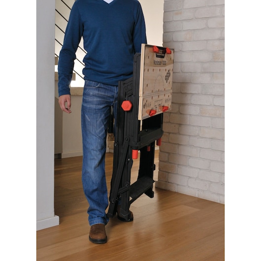 BLACKDECKER WM1000 folding workbench carried by a person indoors, featuring wood and black design.