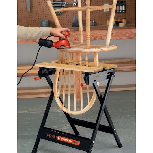 Photo of BLACKDECKER WM301 folding workbench holding a wooden chair for sanding in a workshop.